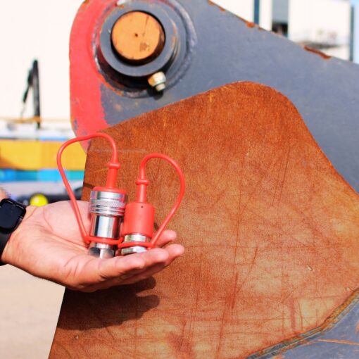 AG12-08N-SET Agricultural Quick Coupler Set resting on a hand in front of construction equipment