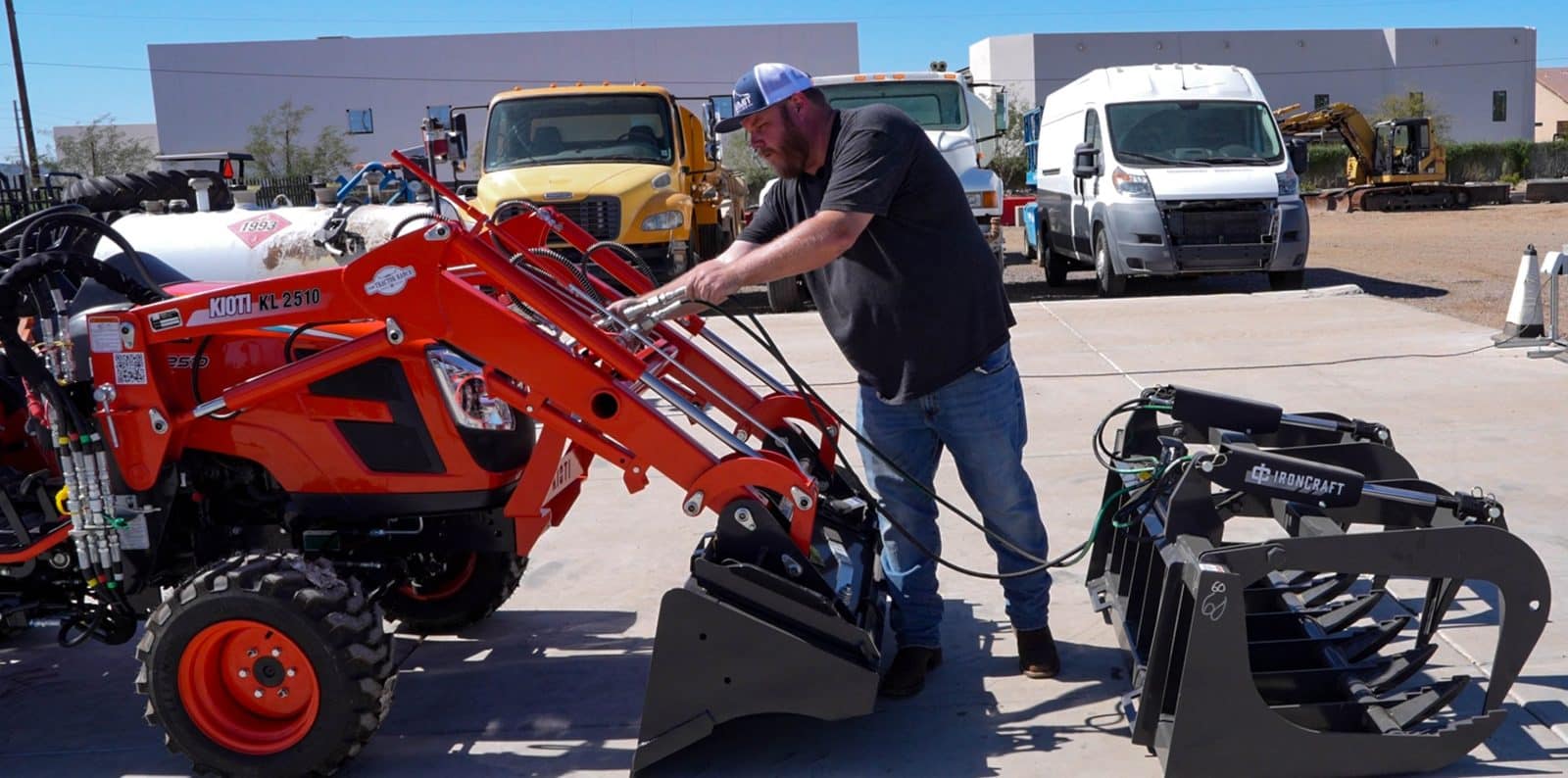Summit Hydraulics employee installing a grapple on a Kioti tractor