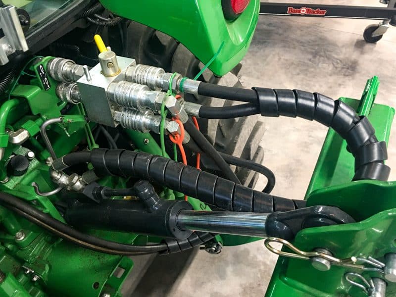 Multiplicador hidráulico manual montado en la parte trasera de un tractor John Deere